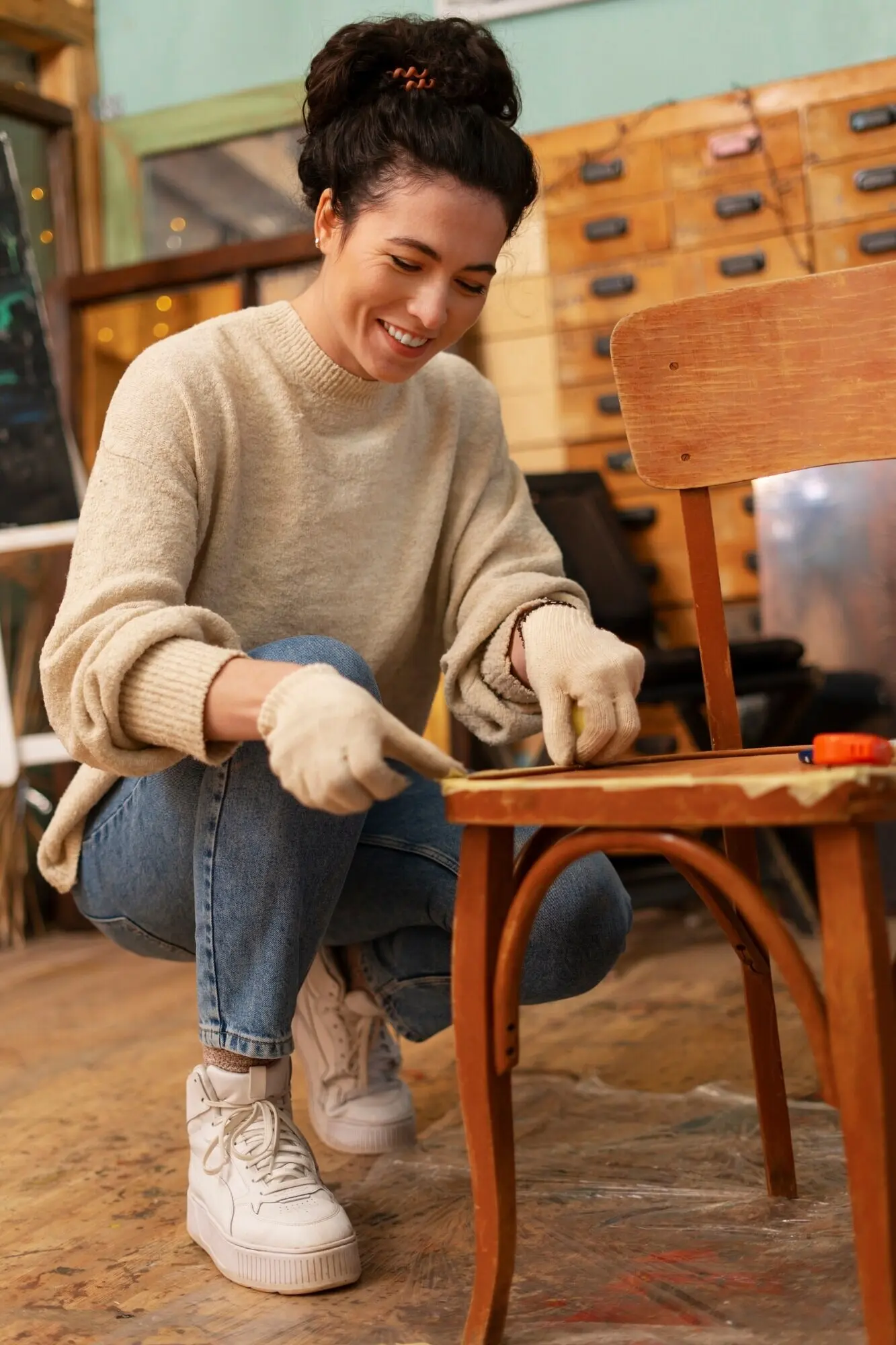 Ganzaufnahme einer Frau, die einen Holzstuhl restauriert.